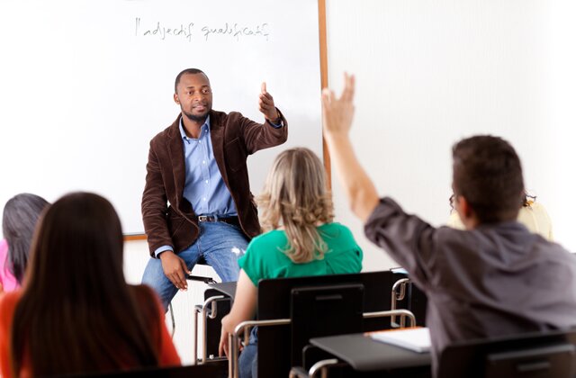 A student raising his hand in front of male teacher to ask about question related to mechanical engineering assignment help