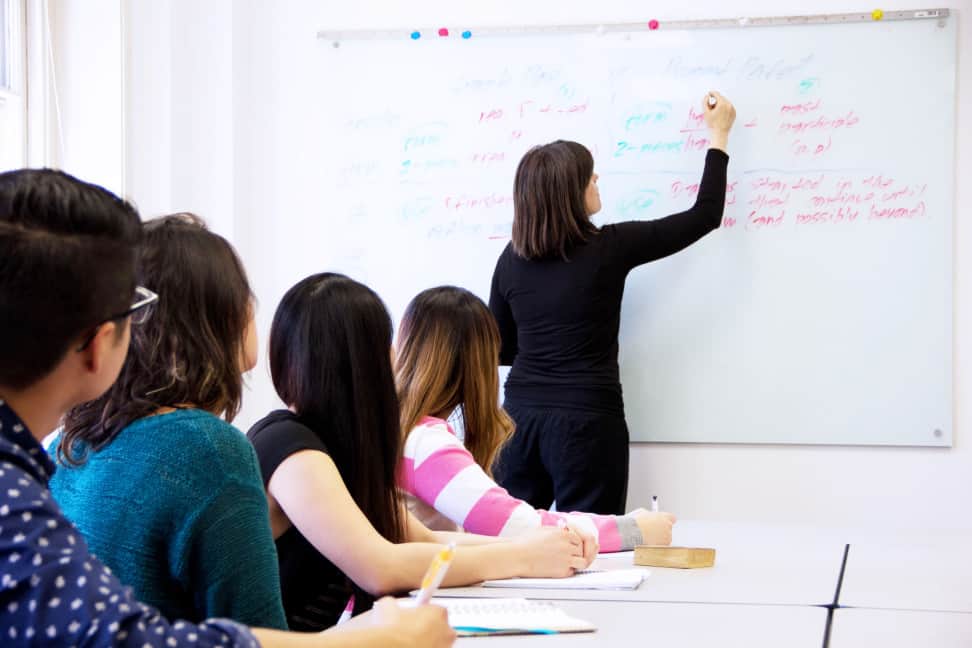 A female tutor explaining human physiology and anatomy concepts to the students in a classroom