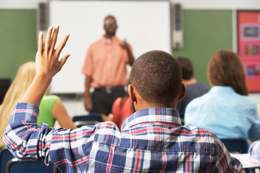 A student in a blue check shirt raising his hand in front of male professor to ask doubt related to zoology topics