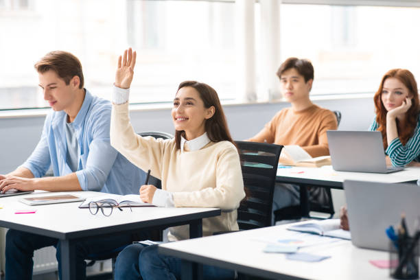 A female student raises her hand in a classroom to ask doubt related to advanced math homework help