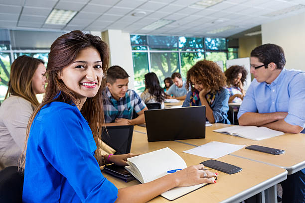 A group of students discuss about their operation research homework and assignment and one female student is giving smile by looking towards the camera