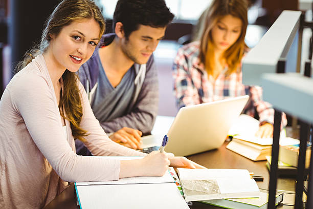 A group of three students sitting on a chair with laptop and notebooks and one female student looking towards camera and smiling they are appear to be engage in physical chemistry Assignment help and physical chemistry homework help