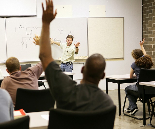 A male professor delivering session on microbiology topics and one student raising his hand to ask question